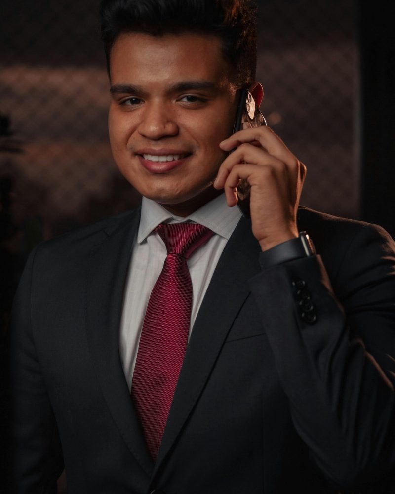 Smiling businessman in a suit making a phone call indoors, showcasing communication and professionalism.