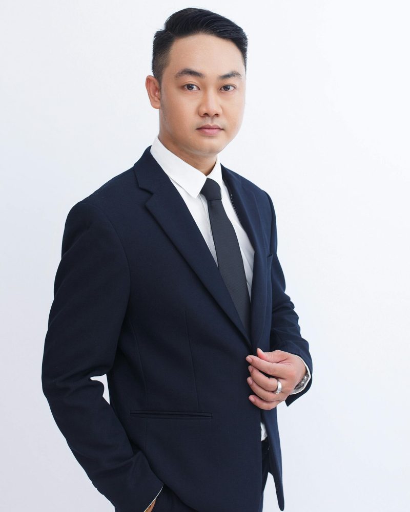 Portrait of a confident businessman in a dark suit against a white background.