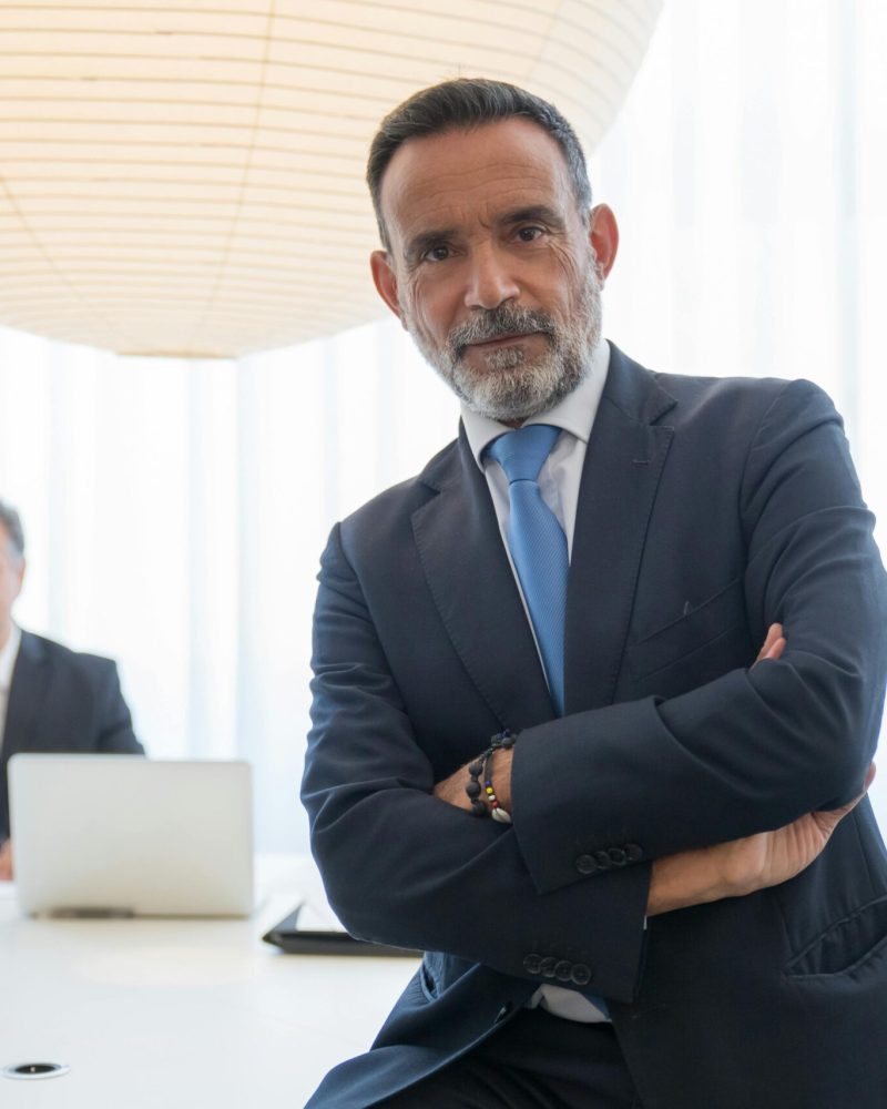 Two businessmen in suits, confidently posing in a modern office setting with a bright, professional atmosphere.